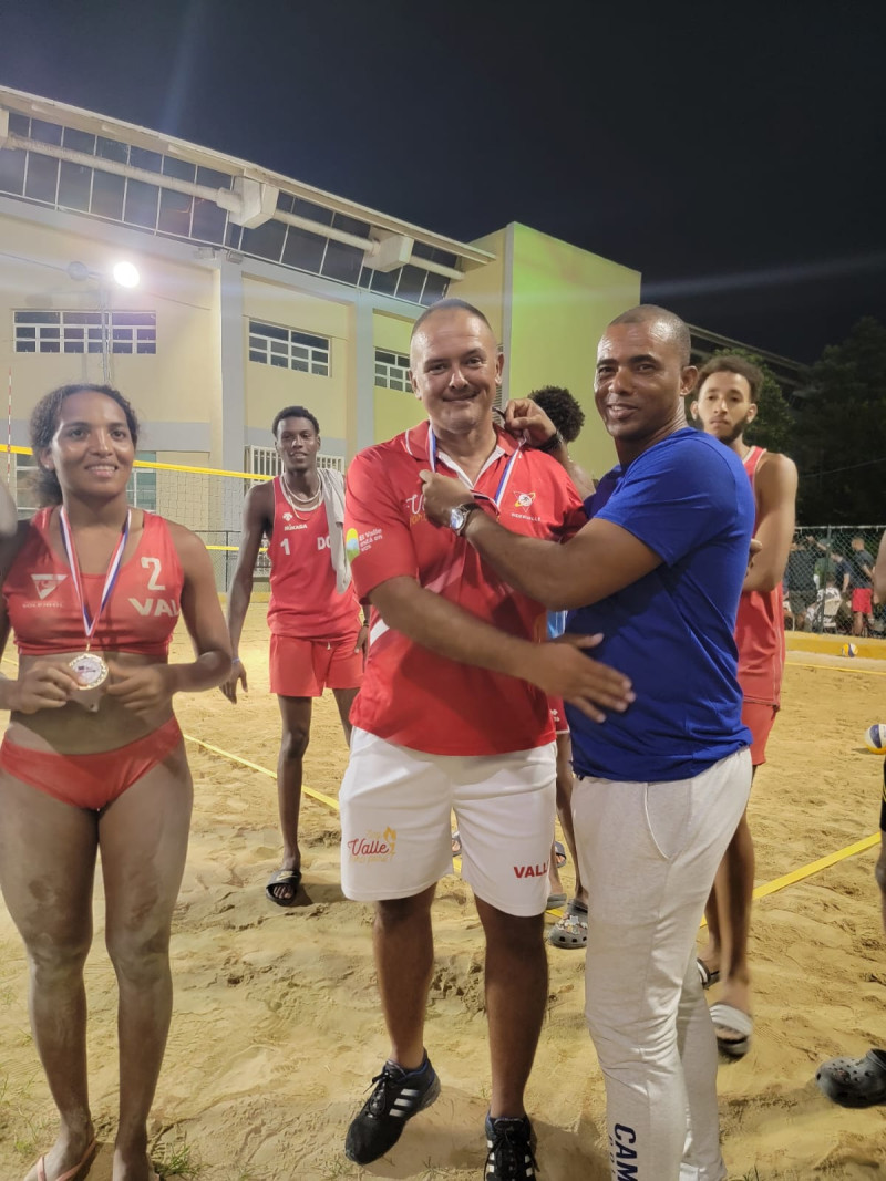 El entrenador del programa de voleibol de playa de República Dominicana, Alexander Massó, coloca una medalla a su par colombiano Jaime Alfredo Beltrán Palma.