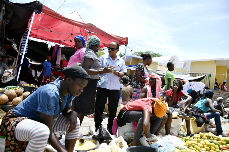 El periodista Guillermo Pérez busca información en espacio de calle donde mujeres y hombres, oriundos de Haití, ofertaban productos, principalmente frutas, habichuelas, ropay otras muchas cosas.