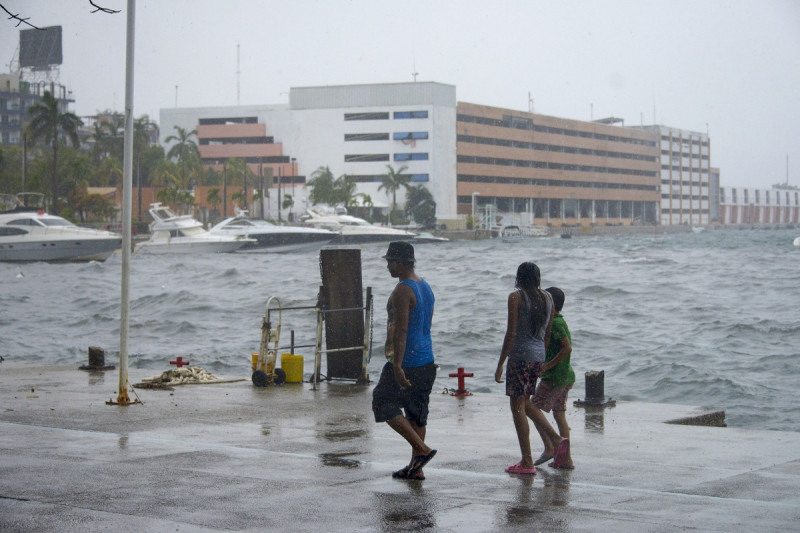 La gente camina a lo largo de la costa en Acapulco, estado de Guerrero, México, el 16 de agosto de 2023, tras el paso de la tormenta tropical Hilary.