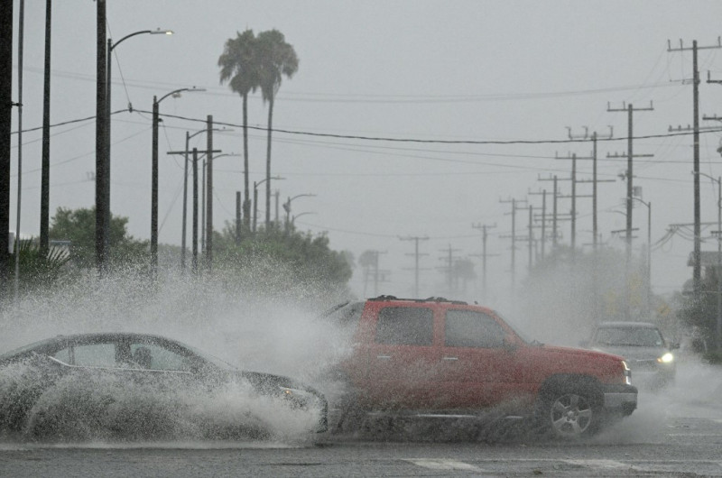 Los vehículos salpican agua durante las fuertes lluvias del huracán Hilary
