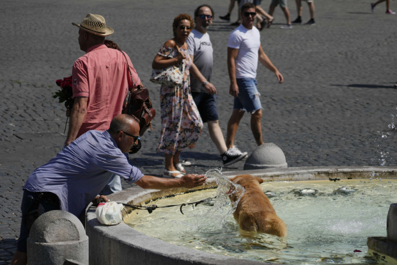 Un hombre refresca a su perro en una fuente en Roma, el martes 22 de agosto de 2023