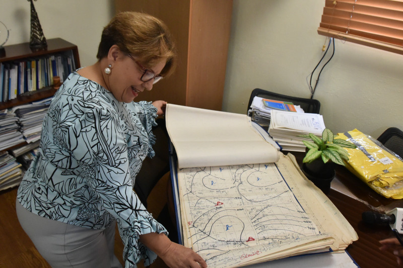 La ingeniera Gloria Ceballos ojea los viejos registros que confeccionaron en 1979 para tratar de seguir el curso del huracán David.
