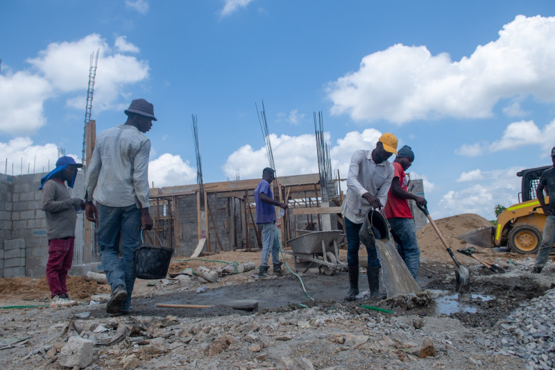 Cinco obreros trabajan con palas y cubos de agua para la mezcla de cemento en el Centro de Retención Vehicular 'La Cuaba'