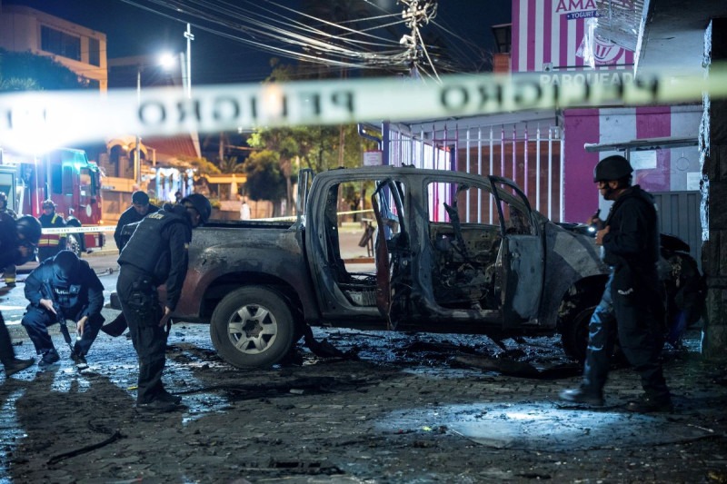 La policía inspecciona una camioneta que explotó afuera de una oficina utilizada por el Servicio Nacional de Atención a Personas Privadas de Libertad que administra el sistema penitenciario en Quito.
