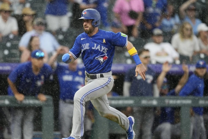 El corredor emergente Mason McCoy anota la carrera de la ventaja gracias a un sencillo de Whit Merrifield en contra del relevista de los Rockies Justin Lawrence.