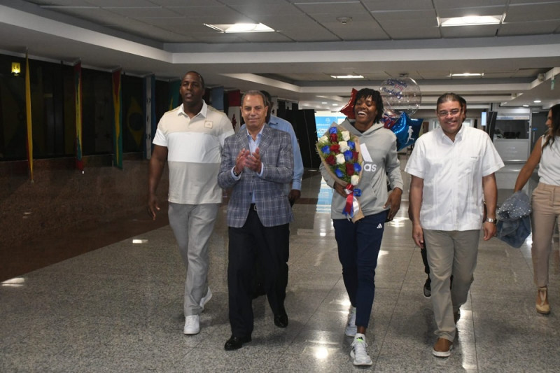 Marileidy Paulino al momento de arribar al país. Fue recibido por el ministro Francisco Camacho y Garibaldy Bautista, titular del COD. Figura su entrenador Jassen Pérez