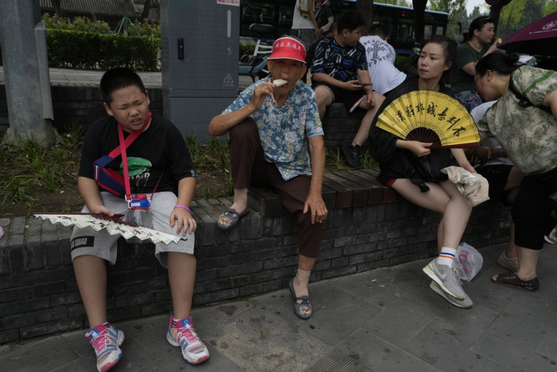 En esta imagen de archivo, turistas toman helados de hielo y se abanican para refrescarse ante las elevadas temperaturas en Beijing, el 9 de agosto de 2023.