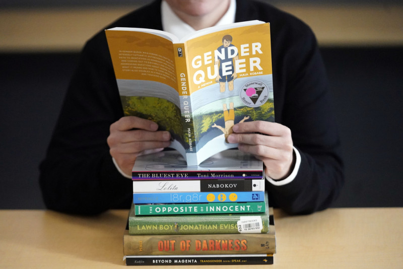 Amanda Darrow, directora de programas juveniles, familiares y educativos en el Utah Pride Center, posa con libros que han sido objeto de quejas de padres, el 16 de diciembre de 2021 en Salt Lake City.