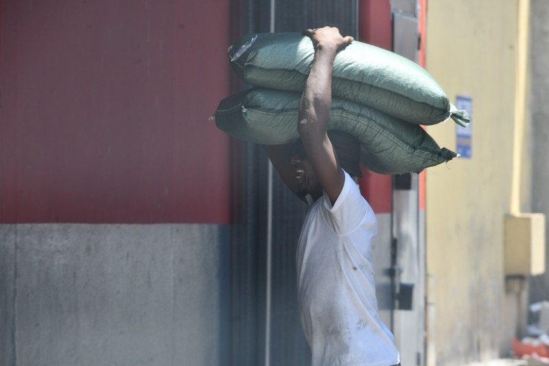 Un hombre de nacionalidad haitiana carga encima de su cabeza dos sacos de arroz hacia un almacén en el 'Pequeño Haití'.