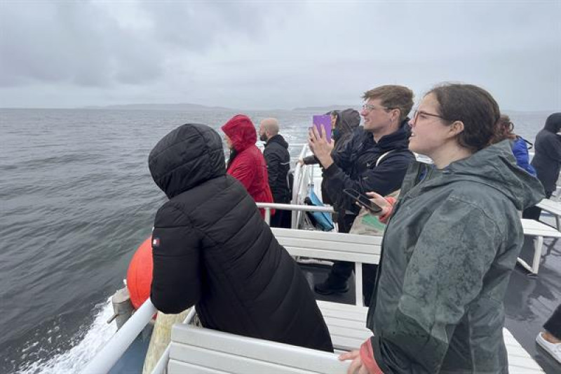 Un grupo de personas participa en una vuelta en barco por el Mar Céltico, organizada para presentar un proyecto que utiliza la IA para proteger a los cetáceos en las costas de Irlanda.