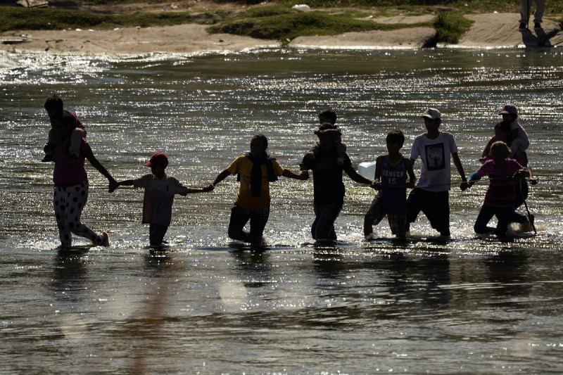 Migrantes forman una cadena humana para cruzar el Río Bravo desde México a Estados Unidos, el 21 de septiembre de 2023, en Eagle Pass, Texas.