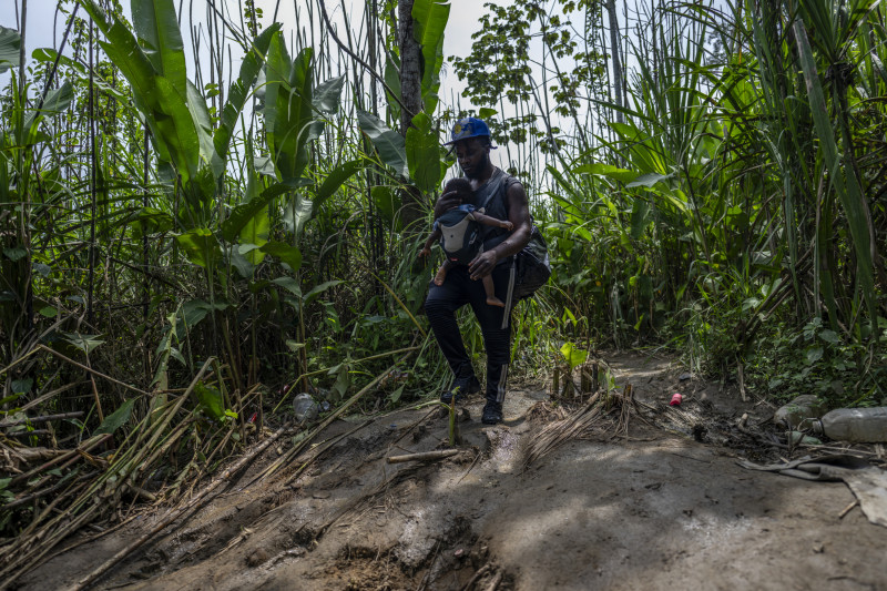 Un migrante que lleva a su bebé camina por la selva cerca de la aldea de Bajo Chiquito, el primer control fronterizo de la provincia de Darién en Panamá.