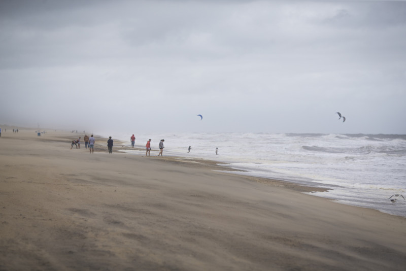 Un grupo de bañistas mira a gente haciendo kitesurf entre las olas provocadas por la tormenta tropical Ophelia, el sábado 23 de septiembre de 2023 en Virginia Beach, Virginia.