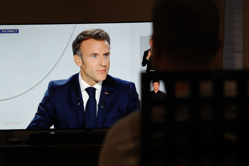 Un hombre observa al presidente de Francia, Emmanuel Macron, en una pantalla de televisión en París durante una entrevista en vivo, ayer.