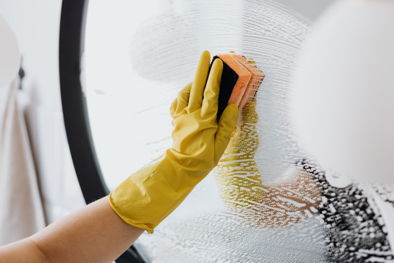 Fotografía ilustrativa muestra mano de trabajadora doméstica limpiando un cristal.