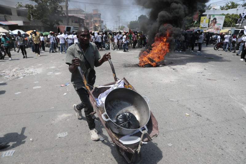 Un hombre empuja una carretilla entre neumáticos incendiados por manifestantes durante una protesta contra la inseguridad en Puerto Príncipe, Haití