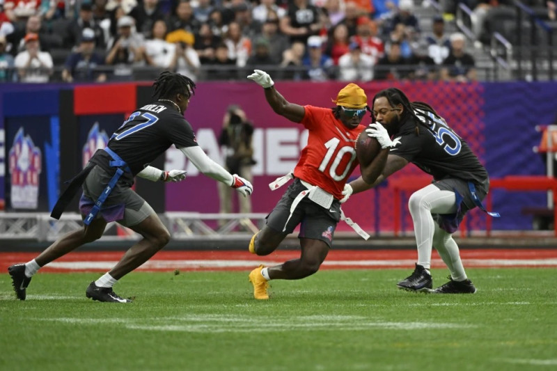 Tyreek Hill acarrea el balón ante la marca de Tariq Woolen y Za’Darius Smith durante un juego de fútbol bandera durante el Pro Bowl de la NFL, en Las Vegas.