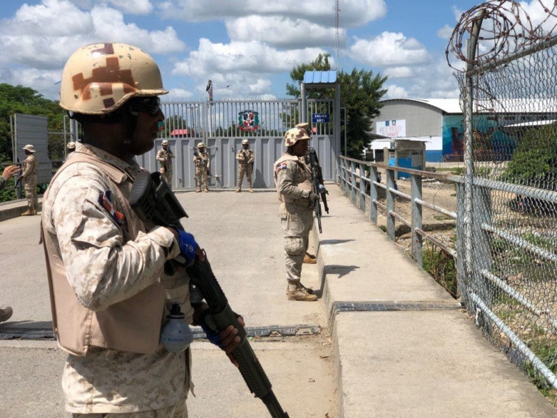 Agentes fronterizos de República Dominicana custodian la puerta que les divide con Haití.