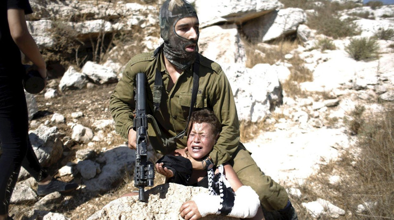 Un soldado israelí domina a un niño palestino que tiene un brazo fracturado durante una incursión militar en Cisjordania.