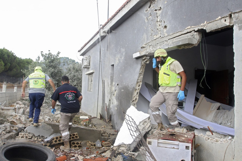 El personal de defensa civil inspecciona una casa bombardeada por las fuerzas israelíes en las afueras de la aldea fronteriza de Dhaira.