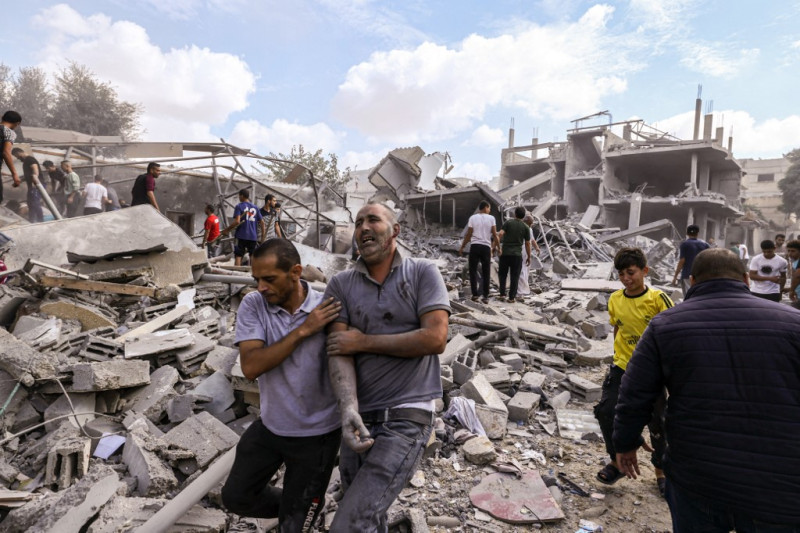 Un palestino reacciona mientras le ayudan a cruzar los escombros tras un ataque aéreo israelí contra edificios en Rafah, en el sur de la Franja de Gaza, el 17 de octubre de 2023, en medio de los continuos combates entre Israel y el grupo palestino Hamás.