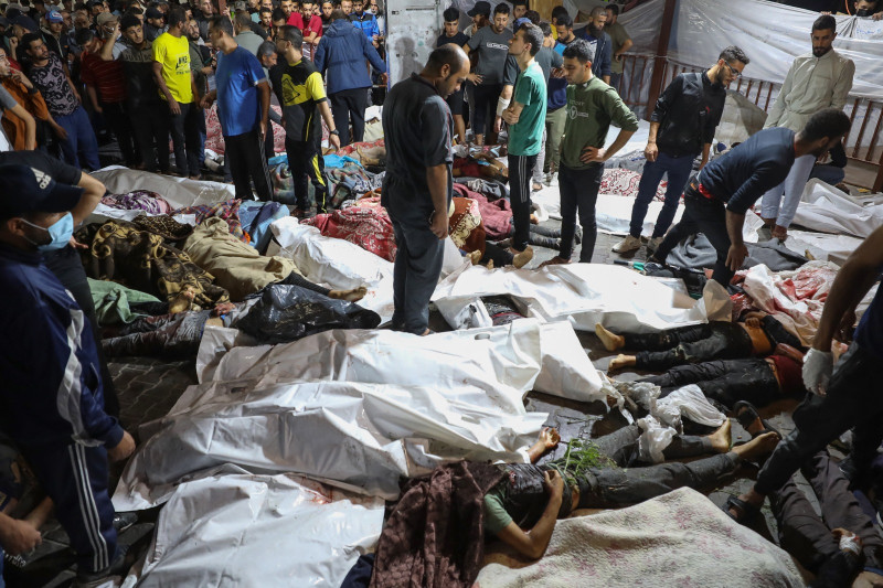La gente se reúne alrededor de los cuerpos de los palestinos muertos en un ataque contra el hospital árabe Ahli en el centro de Gaza.