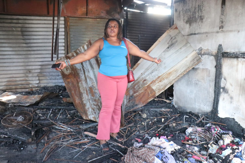 Una mujer que perdió sus mercancías en el mercado fronterizo levanta los brazos, en gesto de desesperación, mostrando los escombros dejados tras el incendio.