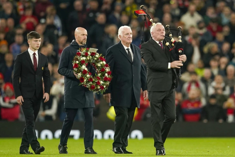 El técnico del Manchester United Erik ten Hag, junto al exjugador Alexander Stepney y el jugador juvenil Dan Gore colocan una guirnalda de flores en honor a Bobby Charlton.