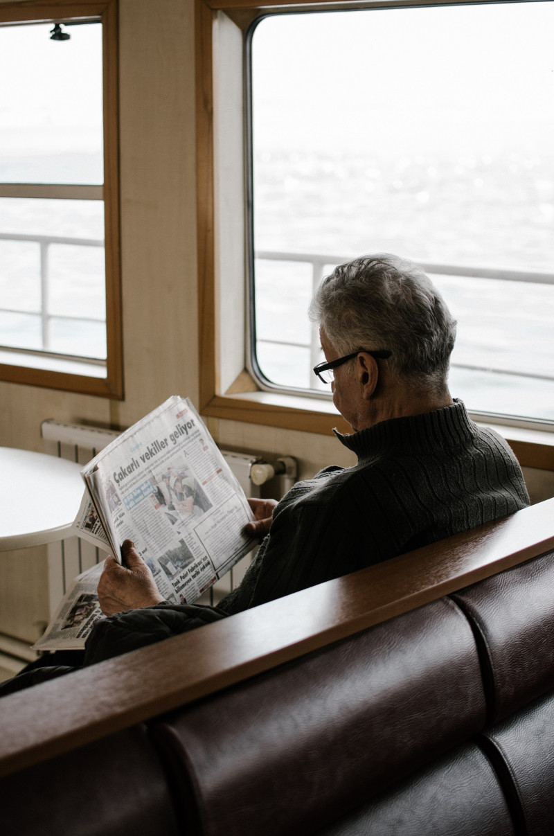 Un señor mientras lee el periódico.