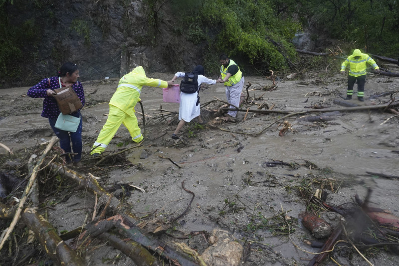 La gente recibe ayuda para cruzar una carretera bloqueada por un deslizamiento de tierra provocado por el huracán Otis cerca de Acapulco, México, el miércoles 25 de octubre de 2023.