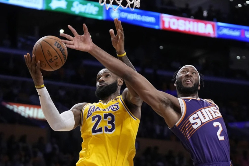 LeBron James, alero de los Lakers de Los Ángeles, atrapa un rebote ante Josh Okogie, de los Suns de Phoenix.