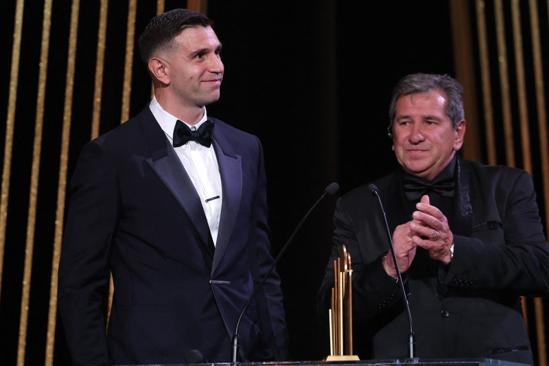 El portero del Aston Villa, Emiliano Martínez (izq.), recibe en el escenario el trofeo Yachine al mejor portero del mundo junto a su padre Alberto Martínez durante la ceremonia de entrega del Balón de Oro de Fútbol de Francia 2023.