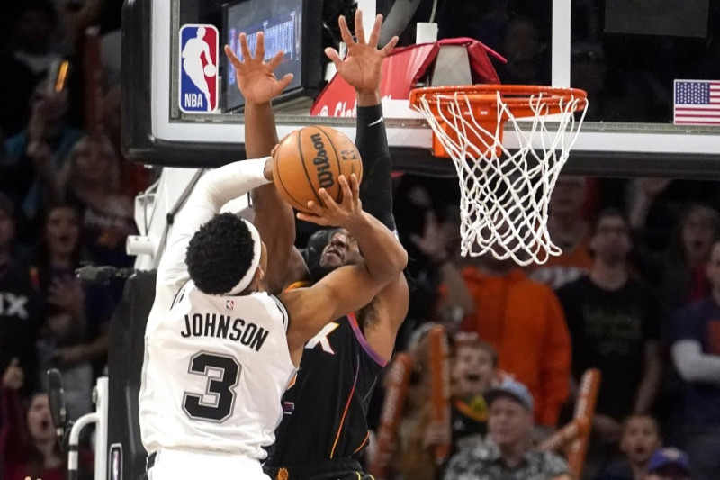 Keldon Johnson, de los Spurs de San Antonio, encesta frente a Josh Okogie, de los Suns de Phoenix.