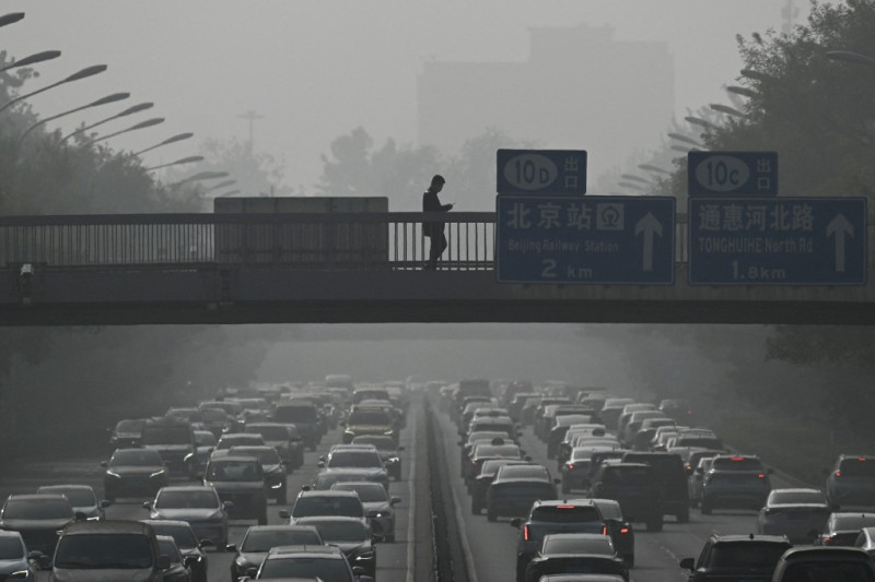 Los peatones caminan por un paso elevado mientras el tráfico se enreda en medio de la neblina provocada por la contaminación del aire en Beijing