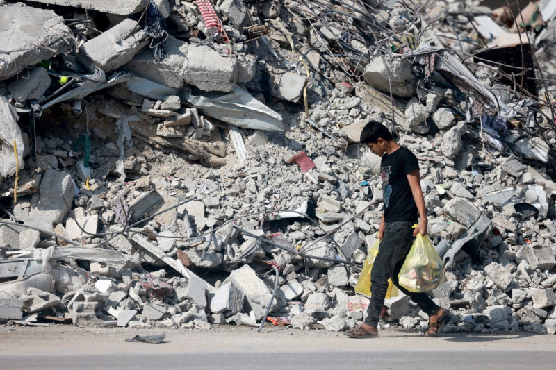 Un joven camina entre escombros de edificios destruidos en Gaza