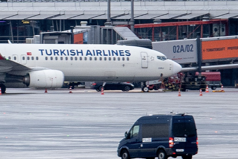 Un furgón policial observa el coche de un secuestrador visto aparcado bajo un avión de una aerolínea turca en la pista del aeropuerto de Hamburgo, norte de Alemania, el 5 de noviembre de 2023