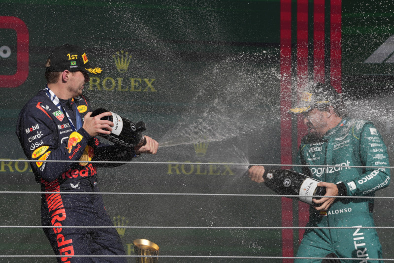 El piloto ganador de Red Bull, Max Verstappen, de Holanda (izquierda), rocía champán en el podio con el tercer lugar, el piloto de Aston Martin, Fernando Alons