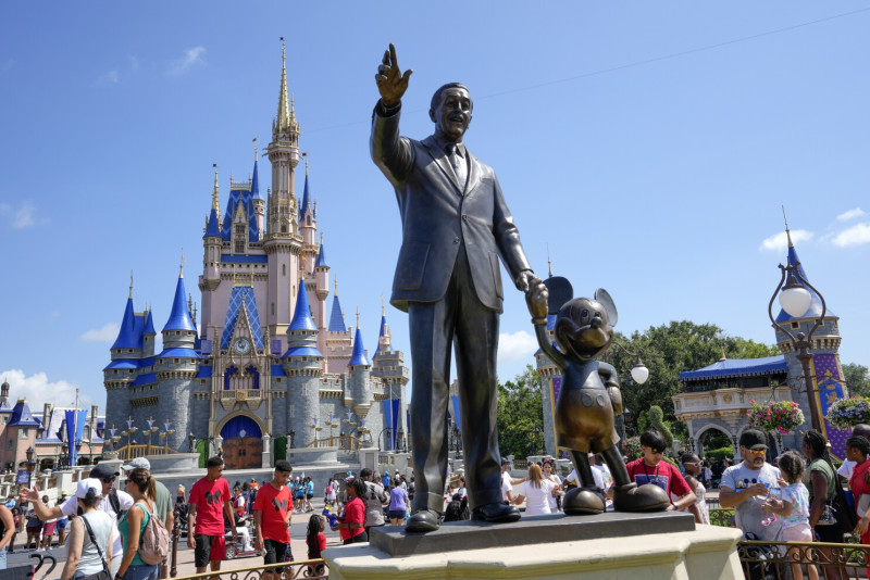 Visitantes del parque temático Magic Kingdom caminan cerca de una estatua de Walt Disney y Mickey Mouse, el viernes 14 de julio de 2023, en Lake Buena Vista, Florida.