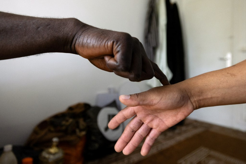 El curandero africano Cheick Issa estrecha la mano de Raymond, uno de sus clientes, antes de una consulta