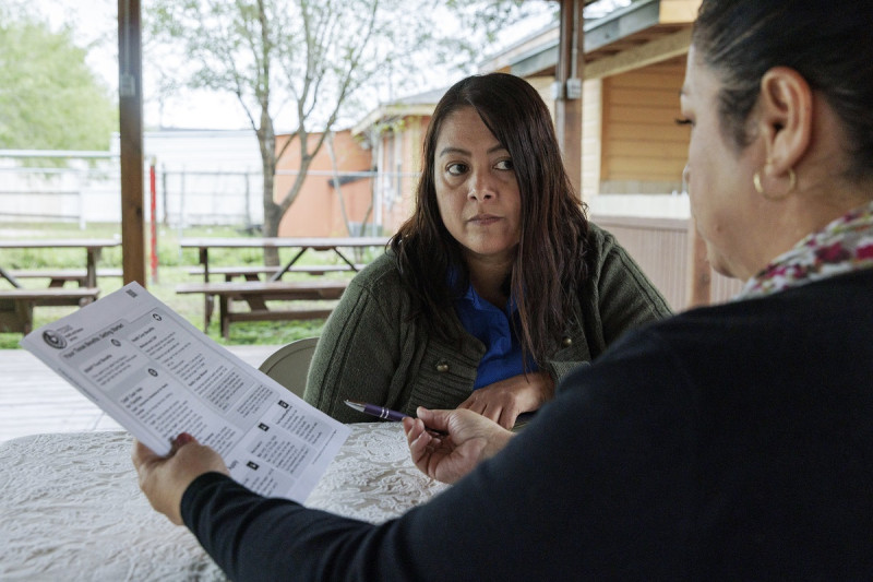La directora del Fondo para la Defensa de los Niños, Graciela Camarena, ayuda a Lucía Salazar a llenar formularios de Medicaid para su familia en Pharr, Texas.