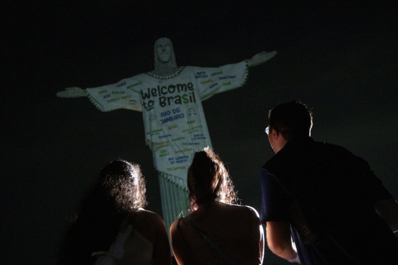 Aficionados miran la estatua del Cristo Redentor iluminada con un mensaje de bienvenida a la cantante estadounidense Taylor Swift, en Río de Janeiro, Brasil