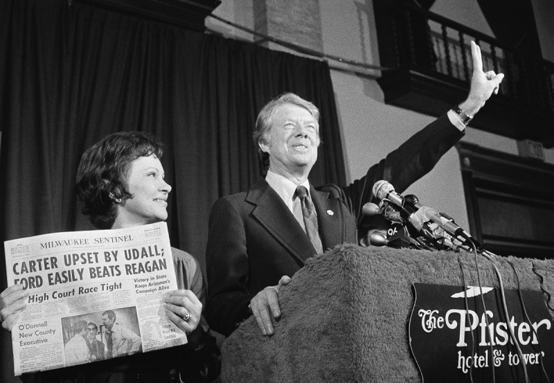 Jimmy Carter hace la señal de la victoria mientras su esposa, Rosalynn Carter, sostiene un periódico después de ganar la primaria presidencial demócrata de Wisconsin el 7 de abril de 1976.