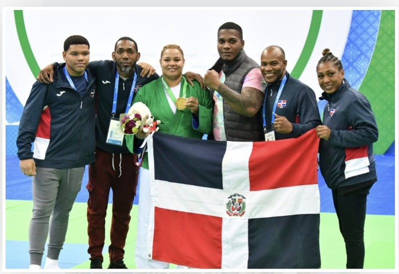 Audrey Puello exhibe la bandera tricolor junto a varios integrantes de la delegación dominicana tras triunfar en la categoría más de 87 kilogramos.