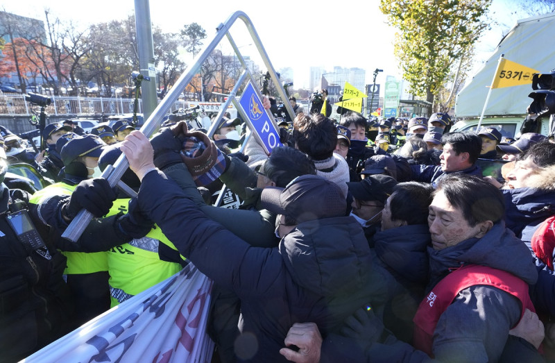 Dueños de granjas caninas chocan con policías frente a la oficina presidencial durante una protesta contra un proyecto de ley encabezado por el gobierno para prohibir el consumo de carne de perro, en Seúl, Corea del Sur, el jueves 30 de noviembre de 2023.