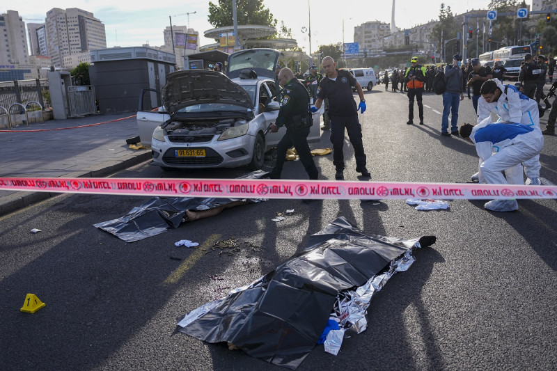 Un agente de policía israelí apunta su arma al cuerpo de un hombre implicado en un ataque en Jerusalén, ayer. Dos hombres asesinaron e hirieron a varias personas en Jerusalén.