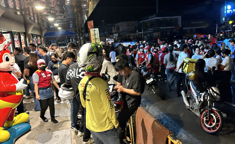 Varias personas se reúnen en una calle tras evacuar el interior de edificios después de que un terremoto sacudiera la ciudad de Butuan, en el sur de la isla de Mindanao