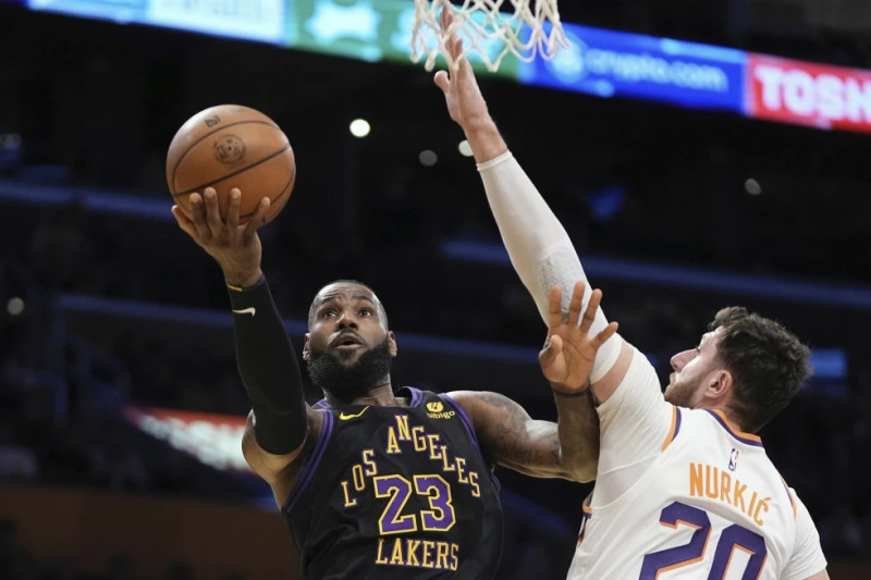 El alero de los Lakers LeBron James lanza el balón a la canasta mientras lo defiende el pívot de los Suns de Phoenix Jusuf Nurkic en el encuentro de la Copa de la NBA.