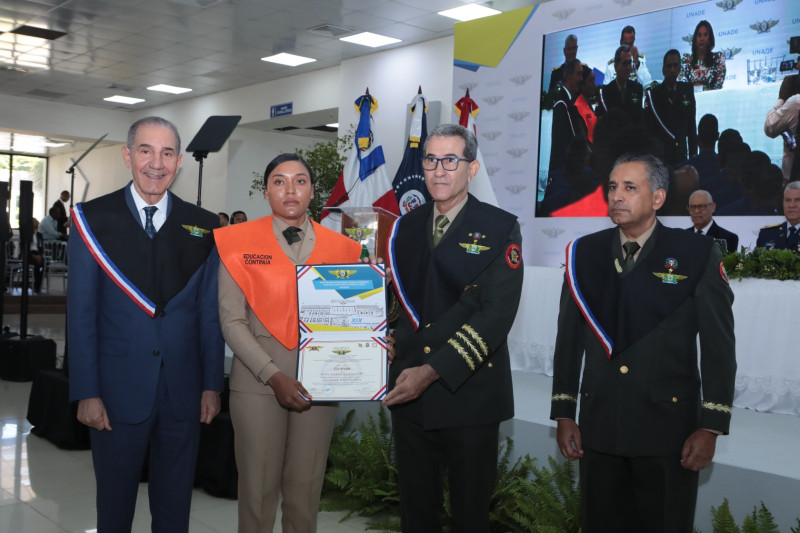 El ministro de Defensa, teniente general Díaz Morfa entrega diploma a una de los graduandos, junto al ministro del Mescyt, Franklin García Fermín.