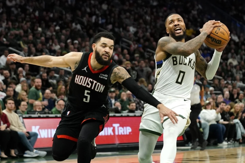 Damian Lillard (0), de los Bucks de Milwaukee, avanza con el balón rumbo a un enceste en contra de los Rockets de Houston, ante la marca defensiva de Fred VanVleet (5).