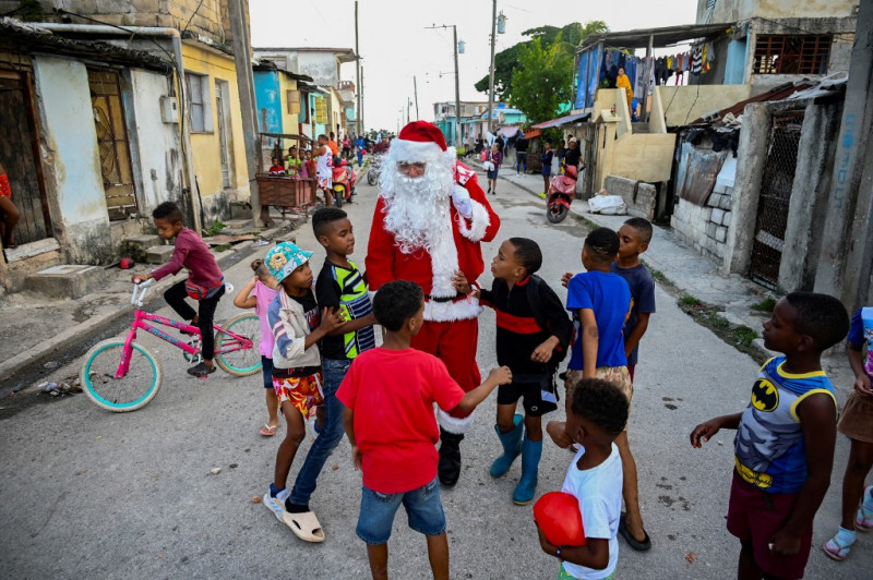 Un hombre vestido de Papá Noel camina con niños por las calles de La Habana el 21 de diciembre de 2023. Con una crisis como la que vive Cuba actualmente, no todos los deseos de los niños pueden hacerse realidad y los padres tienen que hacer magia y malabares para conseguirles juguetes. para Navidad.